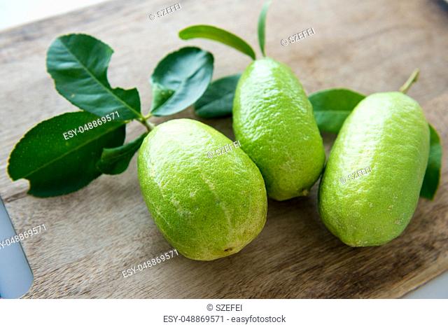 Pesticide free fresh organic lemons with leaves on wooden table background, imperfect insect bites