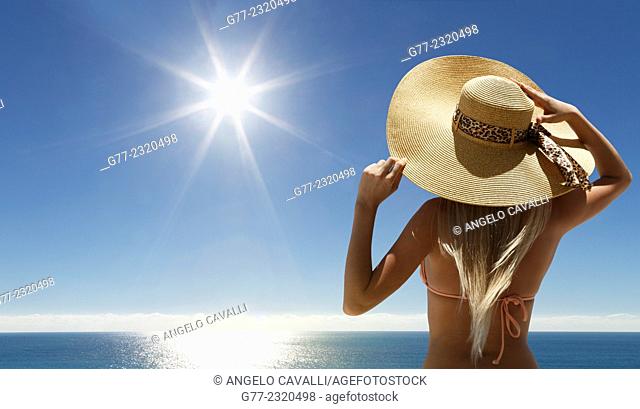 Woman with hat on the beach under sunshine