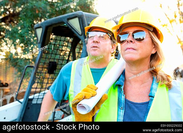 Male and Female Workers With Technical Blueprints at Construction Site