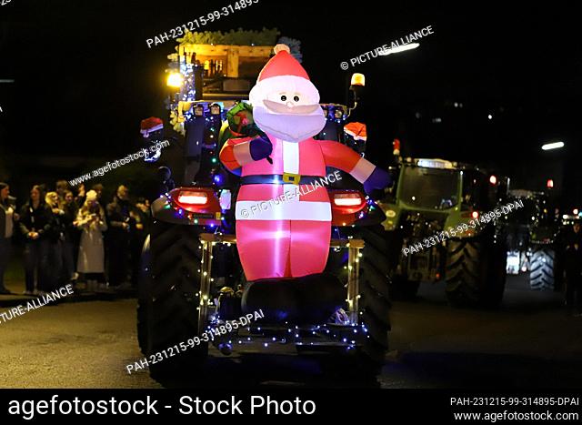 15 December 2023, North Rhine-Westphalia, Kürten: A glowing Santa Claus is attached to a tractor during a tractor light drive
