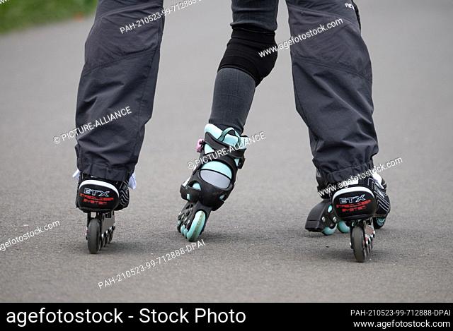 23 May 2021, Hessen, Bad Vilbel: A father is on inline skates with his daughter on an asphalted path on the banks of the Nidd