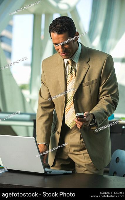 Hispanic businessman with laptop and cell phone