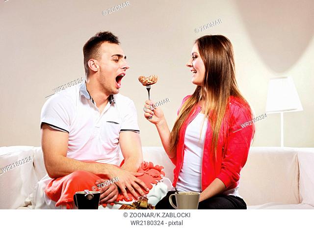 Smiling woman feeding happy man with cake