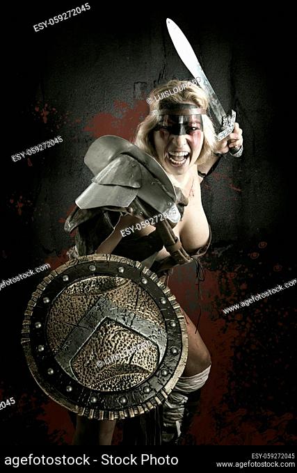 Ancient woman warrior or Gladiator posing with sword and shield, isolated in a dark background