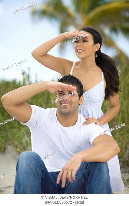 Hispanic couple shielding eyes from sun