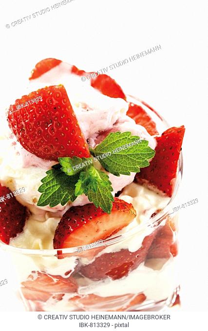 Whipped cream and strawberries garnished with mint leaves served in a parfait glass