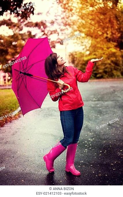 Happy woman with umbrella checking for rain in a park