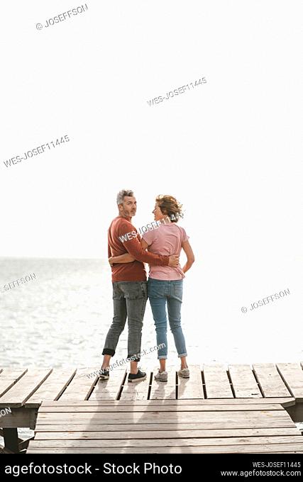 Mature couple with arm around standing on pier