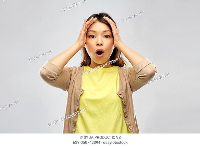shocked asian woman holding to her head