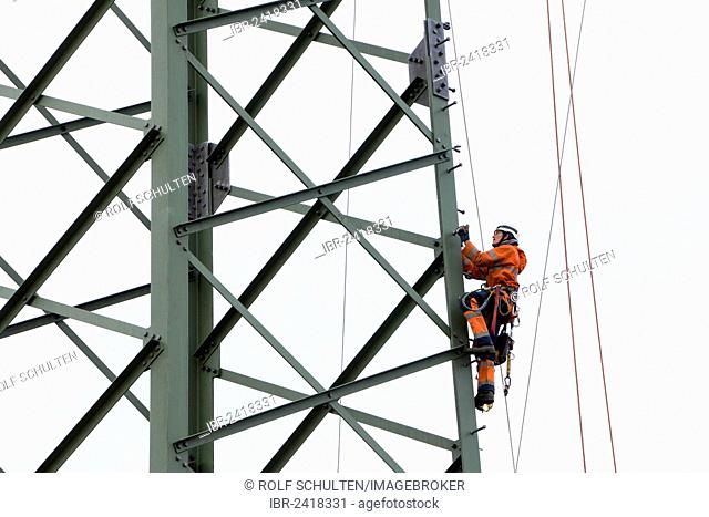 Lineman working with a wire rope hoist on a 380-kV long-distance line owned by the 50Hertz transmission system operator, track cables are being pulled from one...