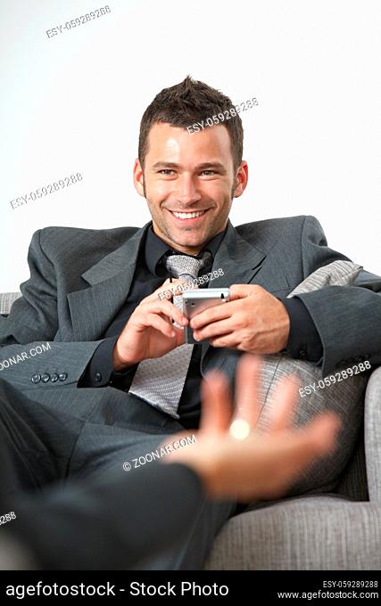Business meeting at office. Happy businessman sitting on sofa, talking, smiling