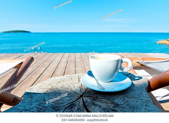 Wooden floor with chaise-longues and cup of coffee on the table, Istria, Croatian coast