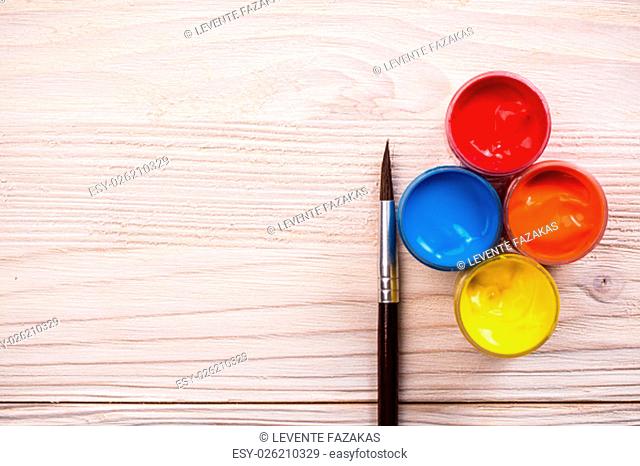Various color paints with brown brush on light wooden backgroud