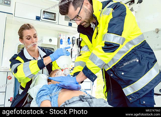 Emergency doctor giving cardiac massage for reanimation in ambulance to boy