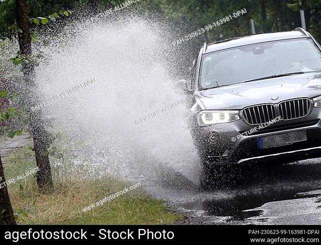 23 June 2023, Berlin: A car drives through a puddle of rain on a side road. Today's continuous rain has put roads in Berlin and Brandenburg under water