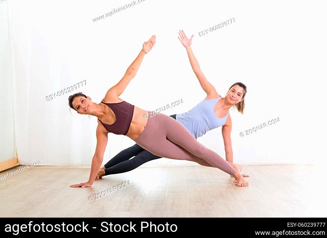 Portrait of active sporty young women practicing yoga in studio. Healthy active lifestyle, working out indoors in gym