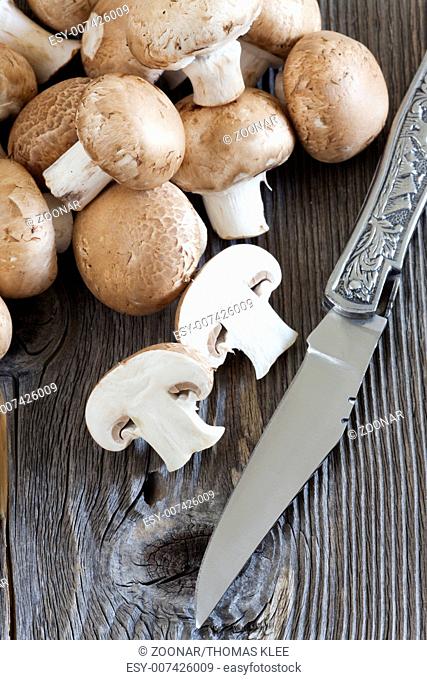 Knife and fresh mushrooms on a rustic wooden board