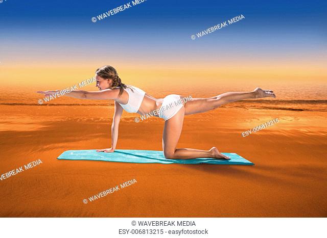 Composite image of gorgeous fit blonde in pilates pose on the beach