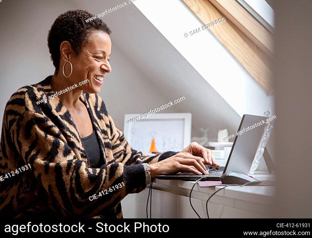 Smiling mature woman working from home at laptop