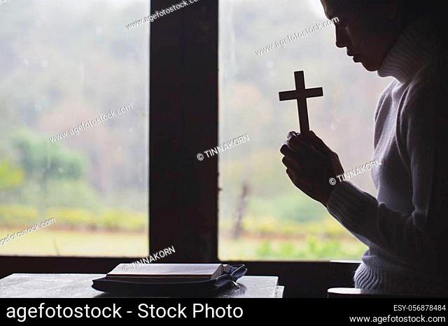 Silhouette of woman praying with cross in nature sunrise background, Crucifix, Symbol of Faith. Christian life crisis prayer to god