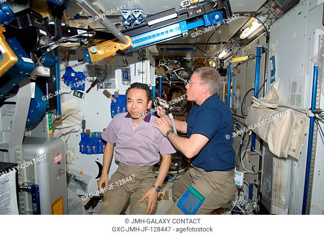 NASA astronaut Mike Fossum, Expedition 28 flight engineer, trims the hair of Japan Aerospace Exploration Agency astronaut Satoshi Furukawa in the Tranquility...