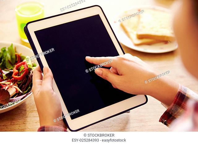 Person Looking At Digital Tablet Whilst Eating Lunch