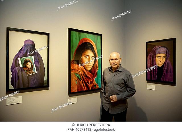 A visitor looks at the photograph 'Woman at the horse festival' ('Frau auf dem US American photographer Steve McCurry stands amongst his pictures in the...