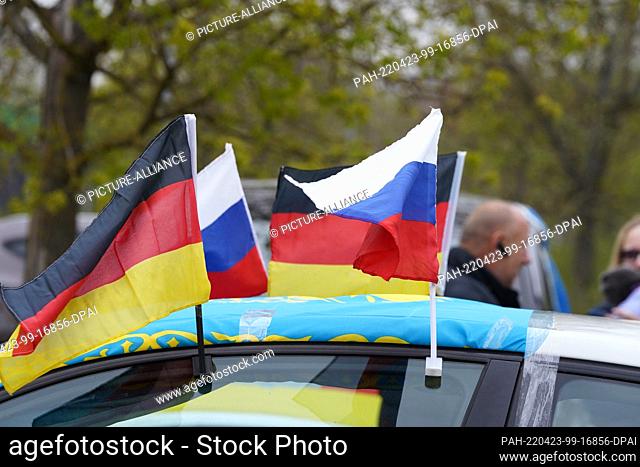 23 April 2022, Reutlingen: People with their cars meet in a parking lot in Reutlingen for a pro-Russian motorcade, with flags waving on one car