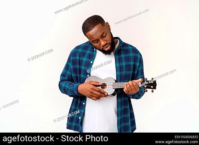 Young handsome african american man plays ukulele isolate over white background