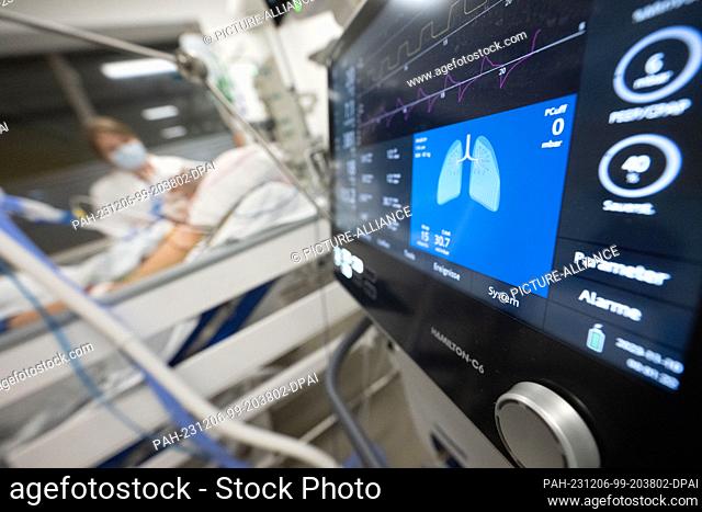 09 November 2023, Deutschland, Stuttgart: A nurse is caring for a patient in an intensive care unit; the monitor of a ventilator can be seen in the foreground