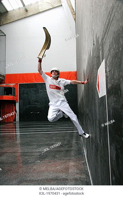 jai alai player catches the ball in his wicker cesta, during a game in Guernica, Spain