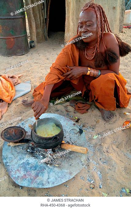 One senior red ochred Himba woman cooking her meal on an open fire, Puros Village, near Sesfontein, Namibia, Africa