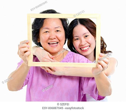 Mixed race Asian senior mother and adult daughter looking fun through an empty frame