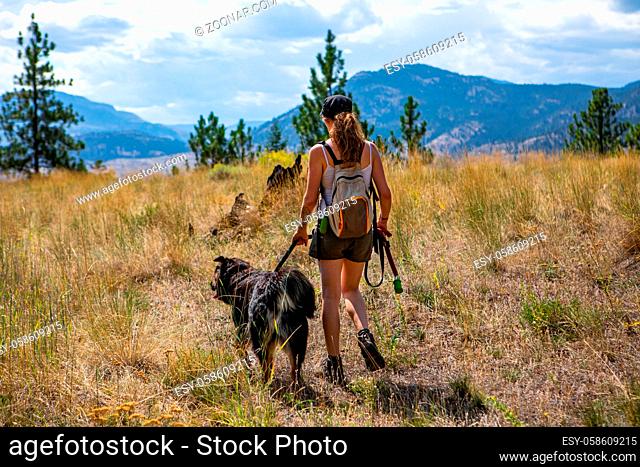 girl in the woods on a dirt road walking and making jogging with her dog on a leash. on dirt road in the british columbia mountains