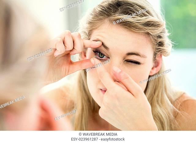 Young woman applying contact lens