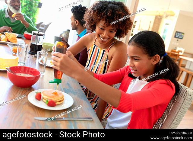 Happy african american family sitting at table smiling during breakfast