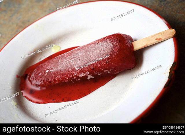 Melting strawberry lolly on a metal plate