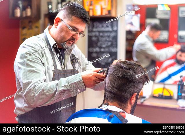 Handsome bearded man getting haircut by hairdresser at the barber shop