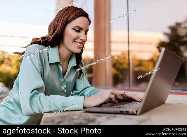 Happy freelancer using laptop outdoors