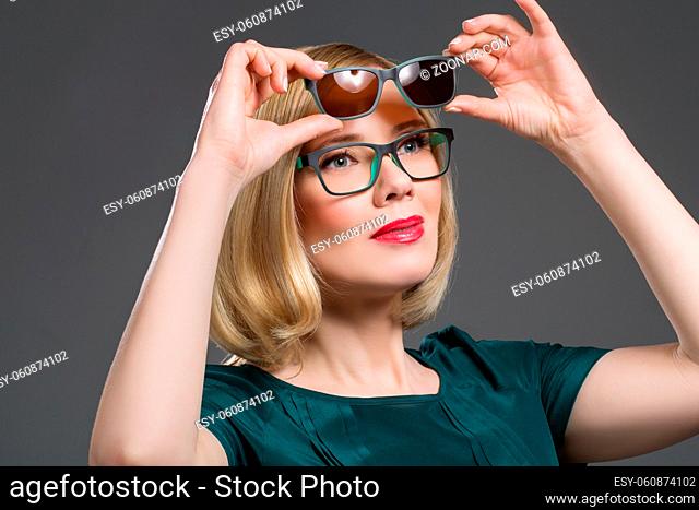 Beautiful middle aged woman with red lips in transformer glasses. Portrait over grey background. Copy space