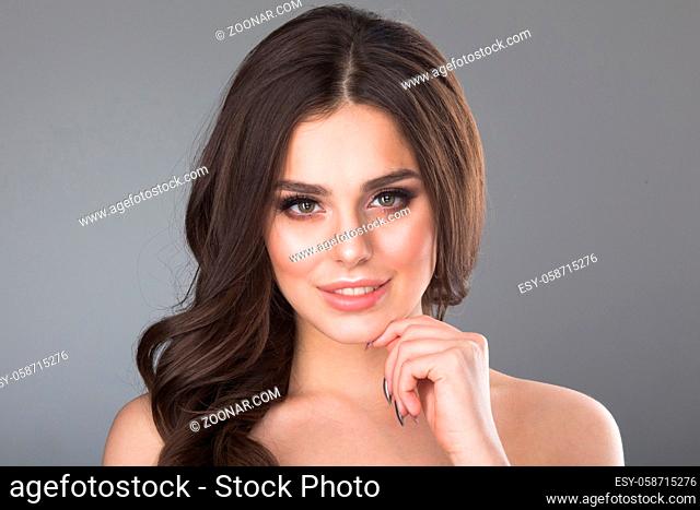 Beautiful young girl touching her perfect skin on gray background. Skin care concept