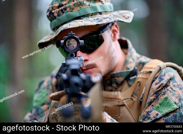 modern warfare soldier in action aiming at weapon laser sight optics in combat position while searching for a target in battle
