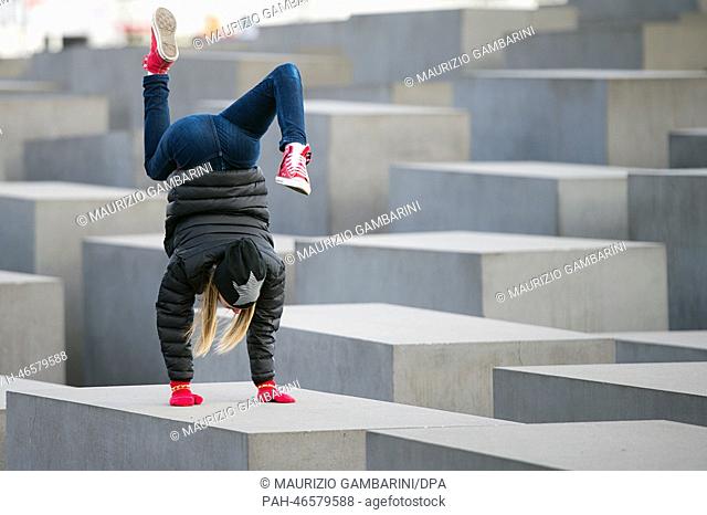 Onur from Finland does a handstand on one of the steles of the Holocaust Memorial during sunny and springlike weather in Berlin, Germany, 22 February 2014