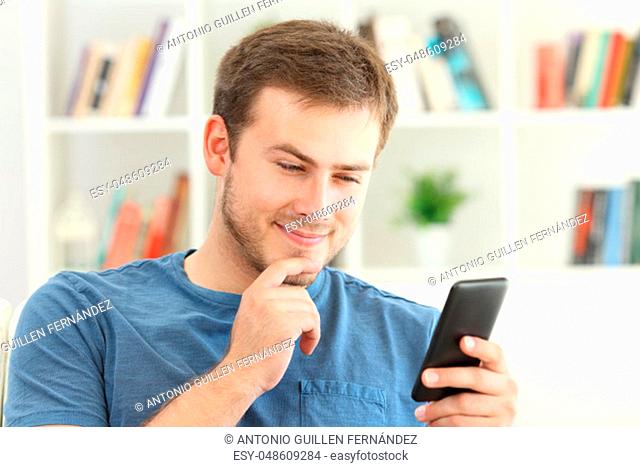 Man dating on line with a smart phone sitting on a sofa at home