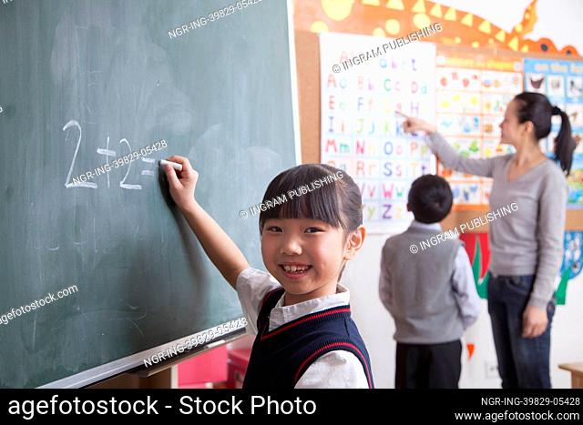 Schoolgirl doing math equation on the black board