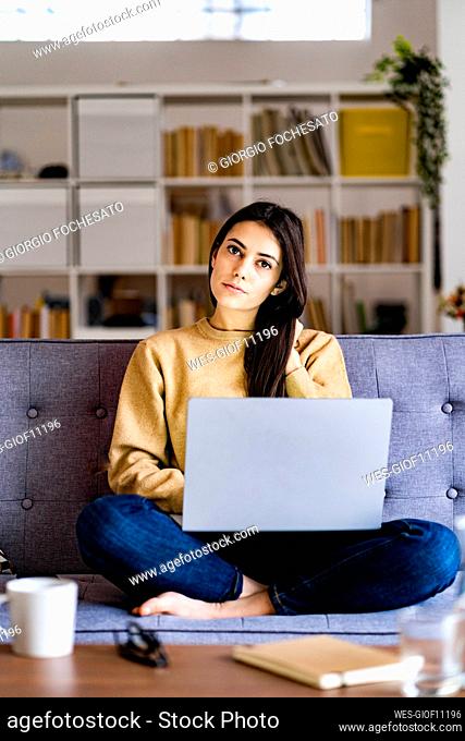 Young woman staring while sitting wit laptop at home