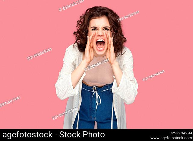 Portrait of beautiful brunette young woman with curly hairstyle in casual style standing, looking at camera and screaming