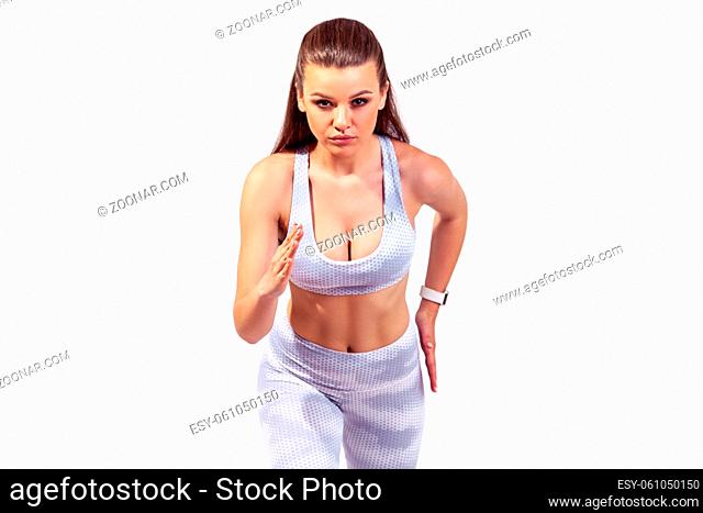 Motivated self confident woman standing on start position ready to run, looking at camera with serious expression, competition