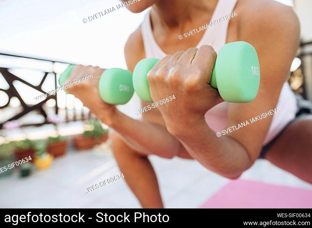 Woman doing exercises with dumbbells on the terrace