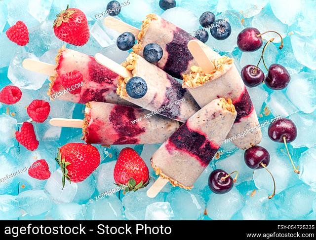 Homemade popsicle and cherry, blueberry, strawberry, raspberry. Healthy summer breakfast concept. Popsicles from yogurt and banana with berries